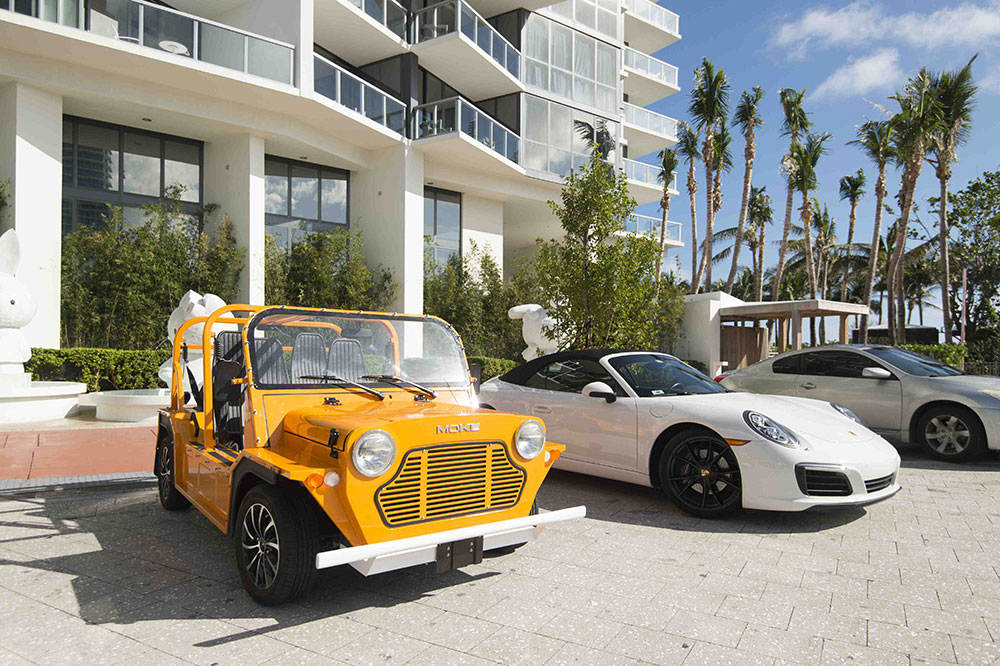 Yellow moke next to white porsche